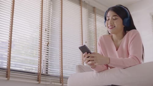 Woman Smiling Looking at Smartphone Wearing Headphones