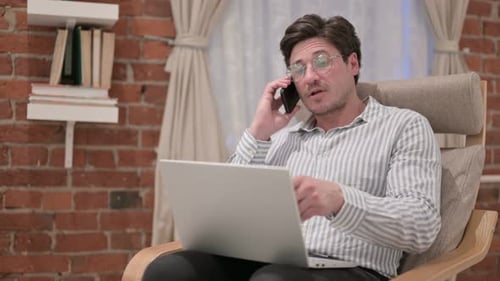 Man Talking on Phone While Using Laptop