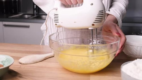 Whisking Eggs On Bowl With Handheld Electric Mixer For Baking A Carrot Cake. - close up