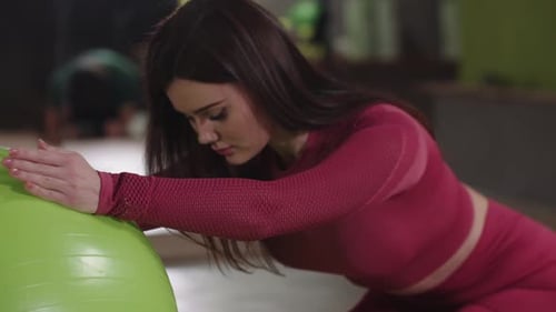 Woman Stretching on Exercise Ball in Gym