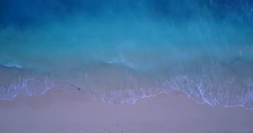 Wide angle birds eye travel shot of a white sandy paradise beach and aqua blue water background in b