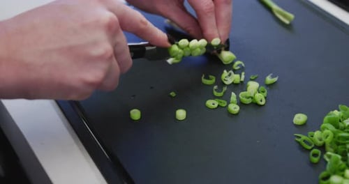 Caucasian female hands slicing spring onions on a cutting board