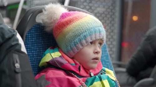 Child on Public Transport with Colorful Hat