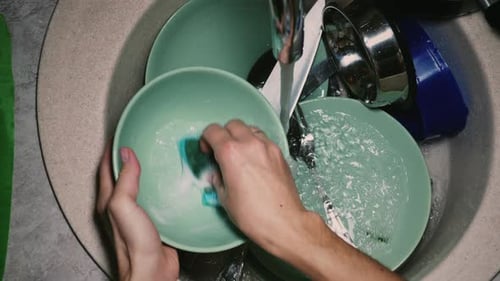Woman washing dishes with a sponge
