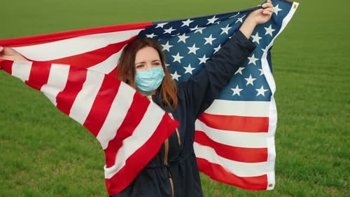 Frau in medizinischer Maske hält Usa-Flagge in ihren Händen