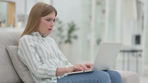 Gestresste junge Frau arbeitet zu Hause am Laptop