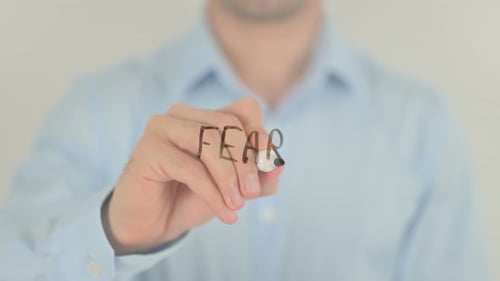 Hand Writes Word Fear on Clear Surface