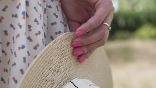 Woman's Hand Holding Straw Hat in Park