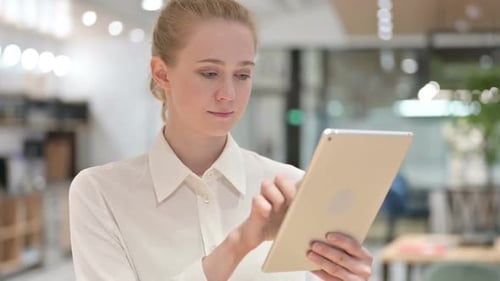 Woman Using Gold Tablet in Bright Office