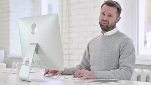 Schockierter junger Mann blickt bei der Arbeit in die Kamera