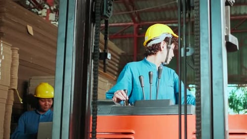 Two female warehouse workers inspect stock, manage cardboard with a forklift.