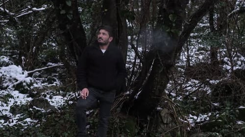 Thoughtful Man Smoking Outdoors in a Snowy Forest
