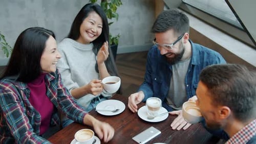 Men and Women Talking and Laughing Sharing News at Gathering in Cafe