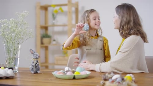Smiling Girl Showing Decorated Easter Egg to Woman