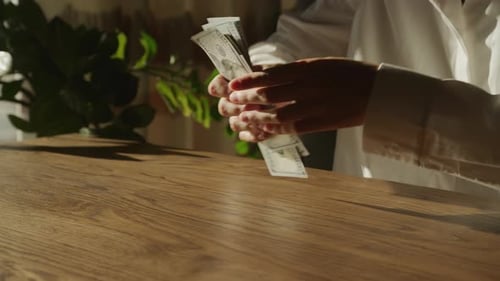 Handheld Close Up of Caucasian Woman Hands Counting Money in 100 Dollar Bill Banknote