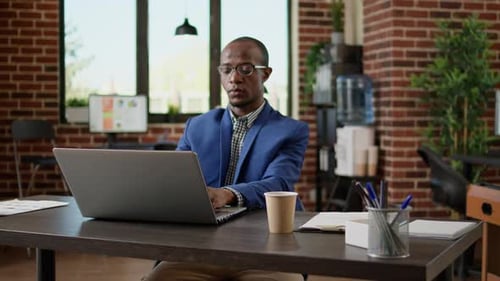 Portrait of Businessman Using Laptop to Browse Internet in Startup Office