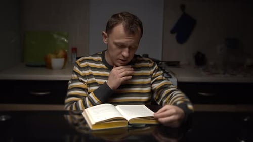 Man Reading a Book at Kitchen Table