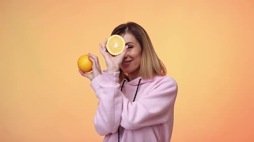 Woman Poses with Oranges in Pink Hoodie