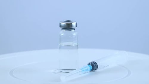 Syringe and Vial of Clear Vaccine on White