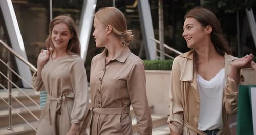 Young Girls Holding Shopping Paper Bags and Walking at City Street, Attractive Millennial Girls