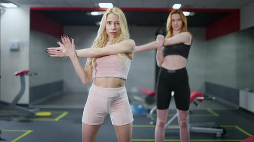 Young Women Stretching Arms in Gym