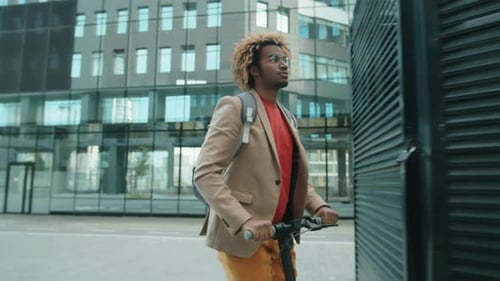 Man Riding Electric Scooter Near Office Building