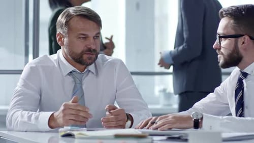 Two Businessmen Talking at Office Table during Meeting