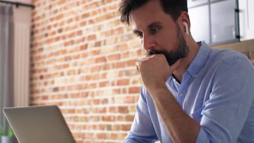 Handheld video of man working using laptop at home office. Shot with RED helium camera in 8K.