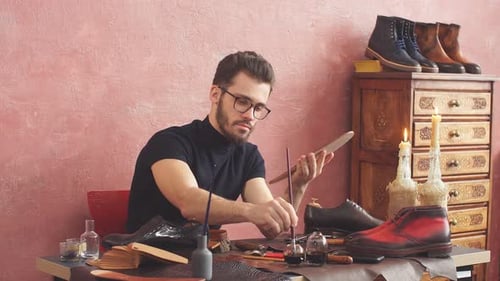 Young Designer Using a Brush While Working in Shoe Shop with Modern Interior