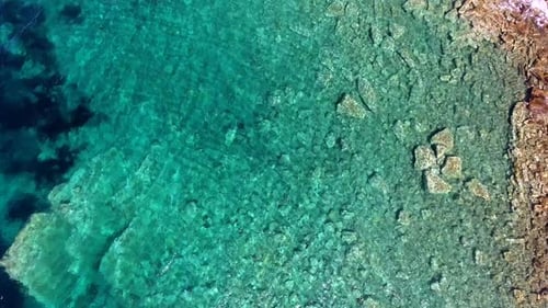 Klares und flaches Meerwasser der Bucht, umgeben von Stein- und Felsküste