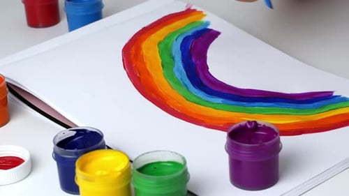 Child Paints a Bright Rainbow on Paper