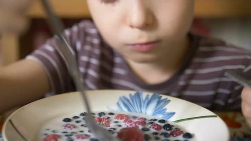 Boy Eating Berries and Milk for Breakfast