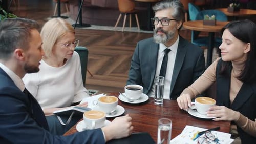 Group of Businesspeople Men and Women Talking in Restaurant Discussing Business