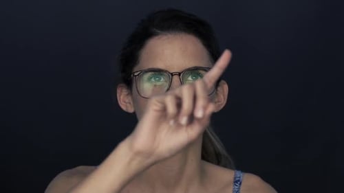Frau mit Brille, schaut nach oben und gestikuliert, als würde sie einen Touchscreen benutzen