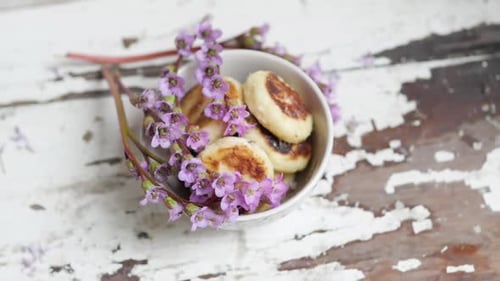 Delicious Syrniki with Purple Flowers on Rustic Surface