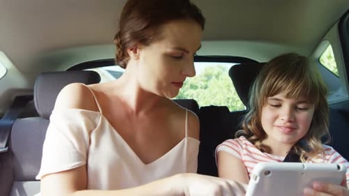 Woman and Child Playing on Tablet in Car