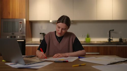 A Pensive Woman Looks at the Documents and the Graphs on the Table Make Notes in the Papers