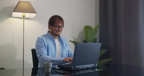 Man Typing on Laptop in Home Setting