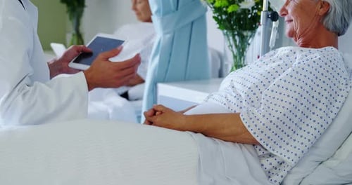 Doctor Showing Tablet to Elderly Patient in Hospital