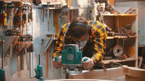 Carpentry Indoors - a Man Woodworker Polishes a Corner of a Wooden Part