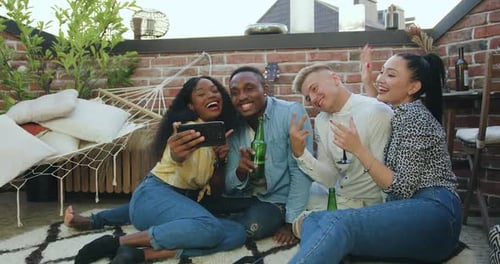 Des jeunes multiethniques s'amusent ensemble tout en ayant un appel vidéo au téléphone avec un ami commun