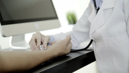 Doctor Checks Patient's Pulse with Stethoscope in Clinic
