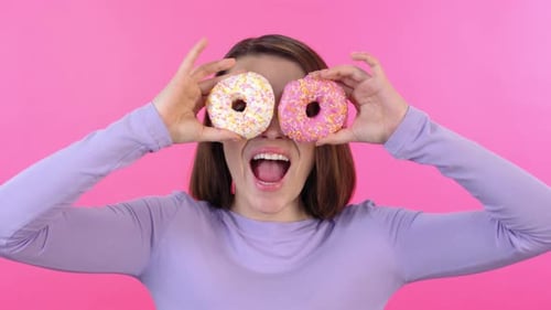 Happy Woman Holding Donuts over Eyes
