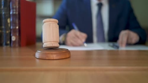 Gavel Sits on Desk with Lawyer in Background