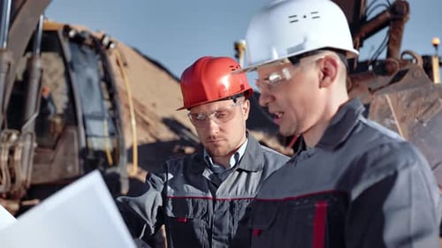 Engineers in Hard Hats Discussing Plans on Construction Site
