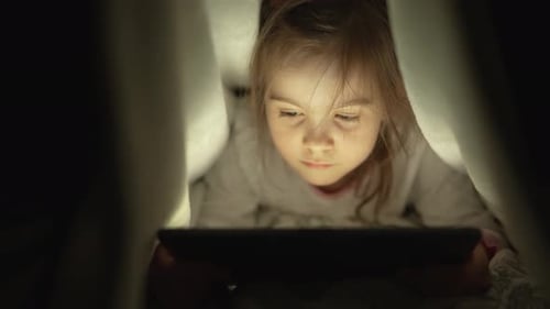 Fille regardant un film sur tablette la nuit