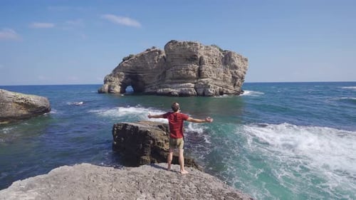 Man Enjoying Ocean View on Rocky Coastline
