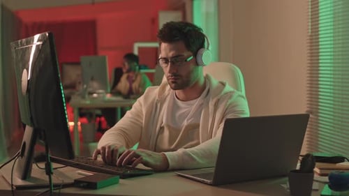 Programmer in Headphones Working in Dark Office
