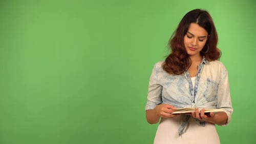 A Young Beautiful Caucasian Woman Reads a Book and Thinks About Something Green Screen Background