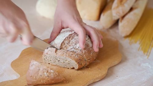 Slicing Grain Bread Loaf on Wooden Board